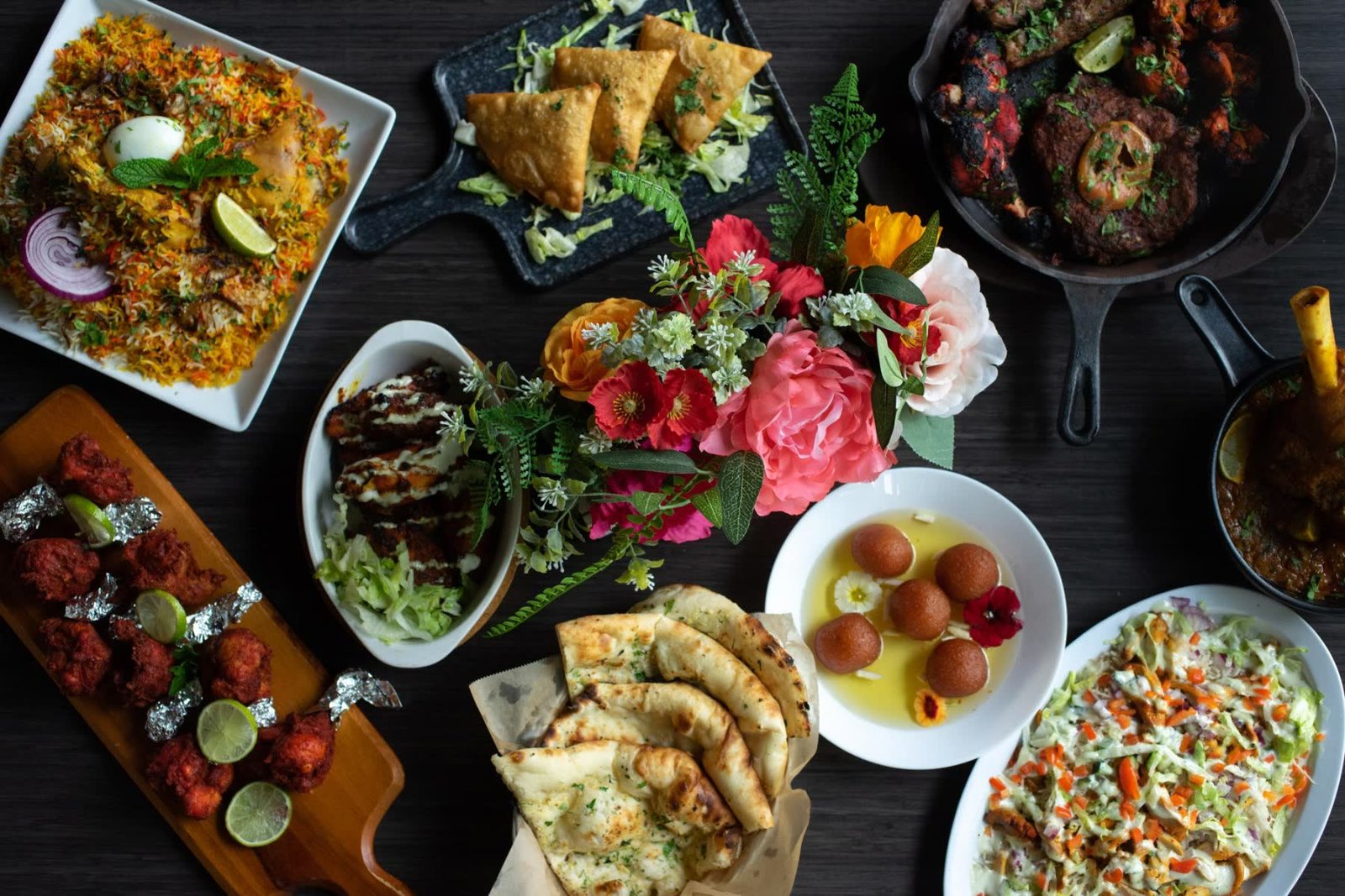 An overhead spread of Naan Curry Grill dishes — biryani, samosas, tandoori, naan and gulab jamun