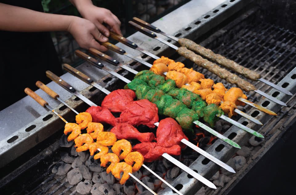 Colourful skewers of shrimp, chicken tikka and seekh kebab on the grill