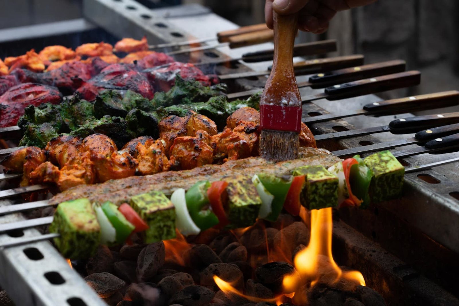Tandoori chicken and tikka skewers grilling over charcoal flames